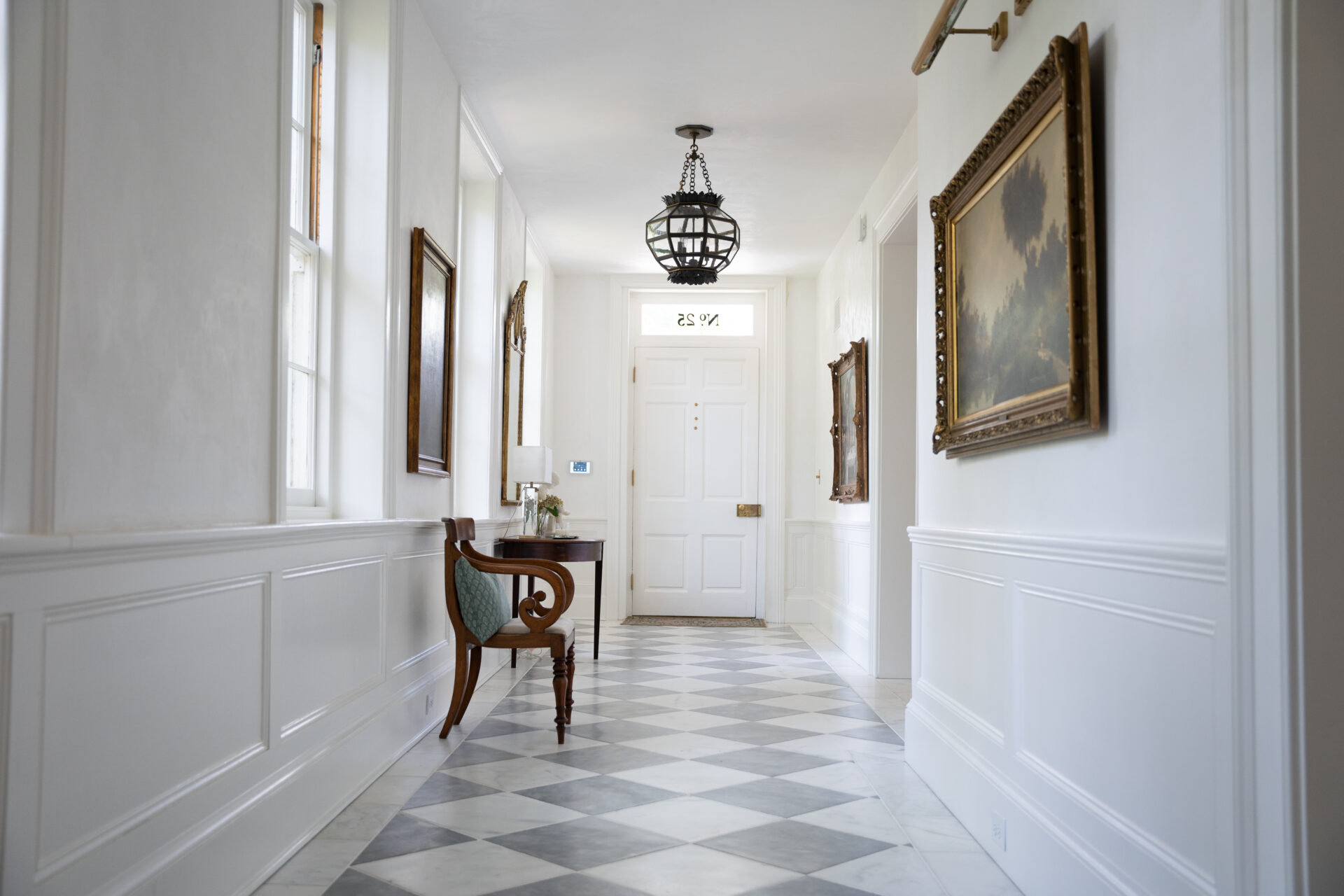 A hallway with white walls and black and white floor.
